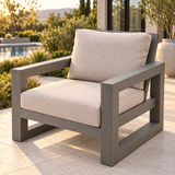 Fauteuil Ratana Milano à structure en aluminium gris Opal Grey et coussins clairs, présenté sur une terrasse