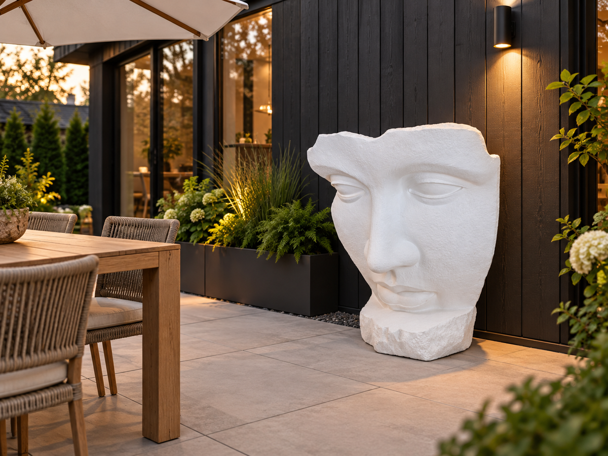 Sculpture de visage Atoll blanche sur une terrasse devant un revêtement extérieur foncé