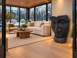 Sculpture de visage Atoll noire à l’intérieur d’un solarium avec vue sur un jardin enneigé